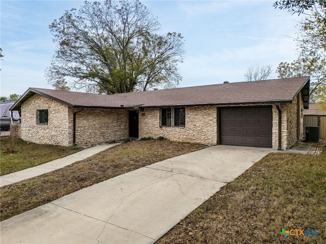 ranch-style home with a front lawn, cooling unit, and a garage