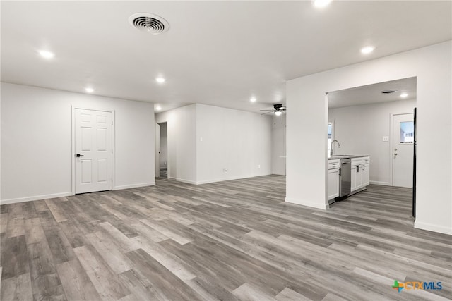 unfurnished living room featuring light wood-type flooring, ceiling fan, and sink