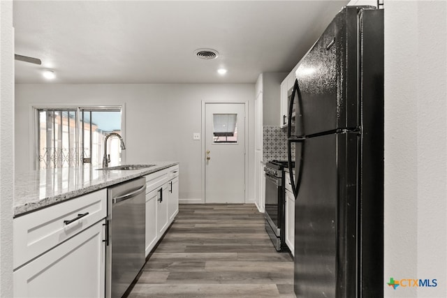 kitchen featuring light stone counters, stainless steel appliances, dark wood-type flooring, sink, and white cabinets