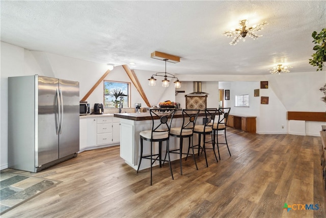 kitchen with stainless steel appliances, hardwood / wood-style flooring, and white cabinetry