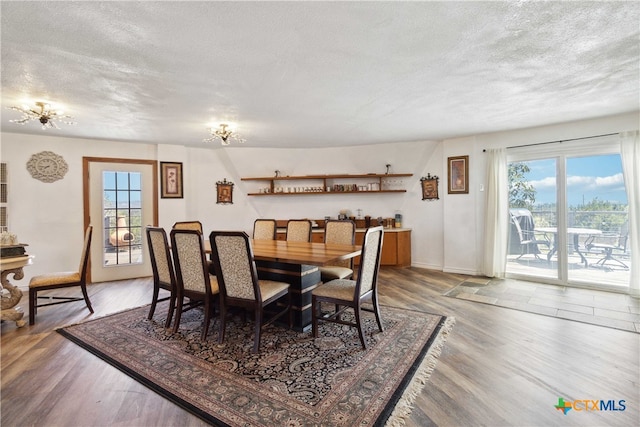 dining space with hardwood / wood-style floors, a healthy amount of sunlight, and a textured ceiling