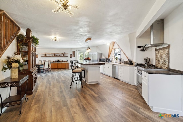 kitchen featuring stainless steel appliances, white cabinetry, a textured ceiling, a breakfast bar, and kitchen peninsula