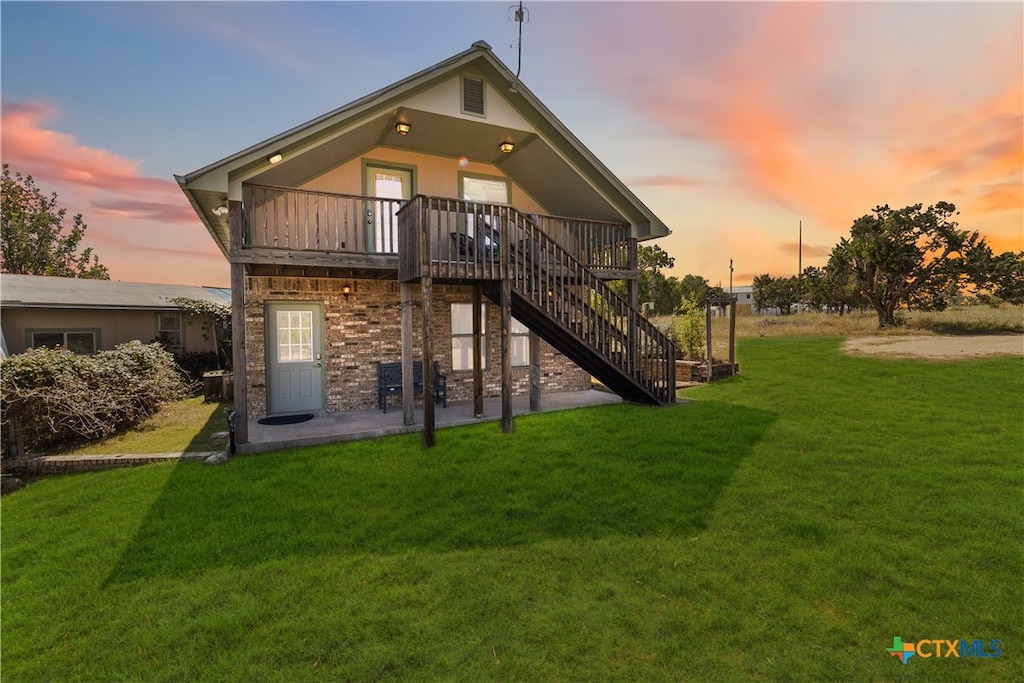 back house at dusk with a wooden deck and a yard