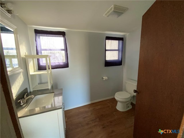 bathroom with vanity, toilet, wood-type flooring, and a wealth of natural light