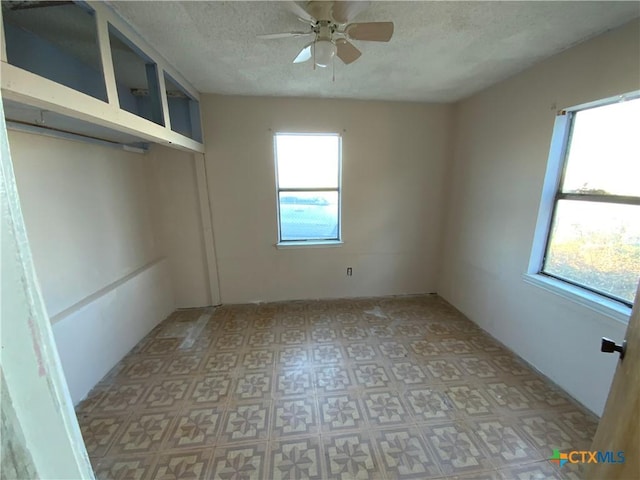 empty room with a textured ceiling and ceiling fan