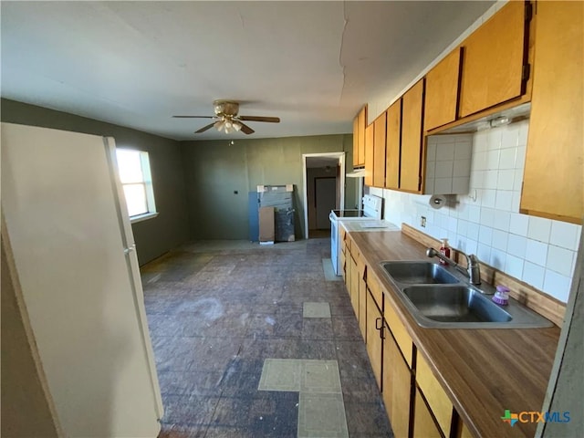 kitchen with backsplash, ceiling fan, sink, and range