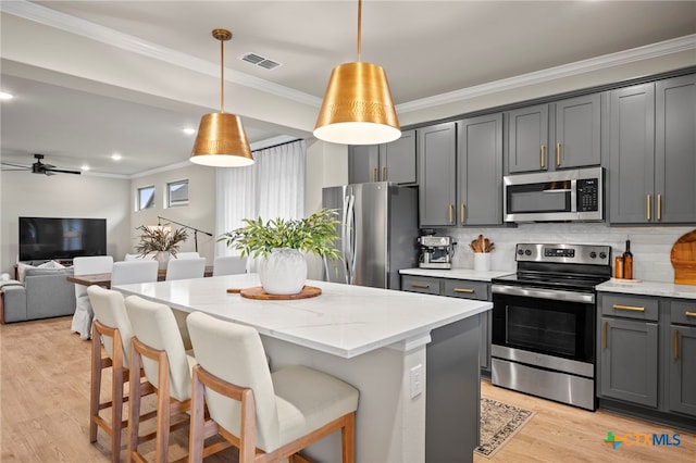 kitchen featuring decorative backsplash, stainless steel appliances, light wood-type flooring, light stone countertops, and ornamental molding