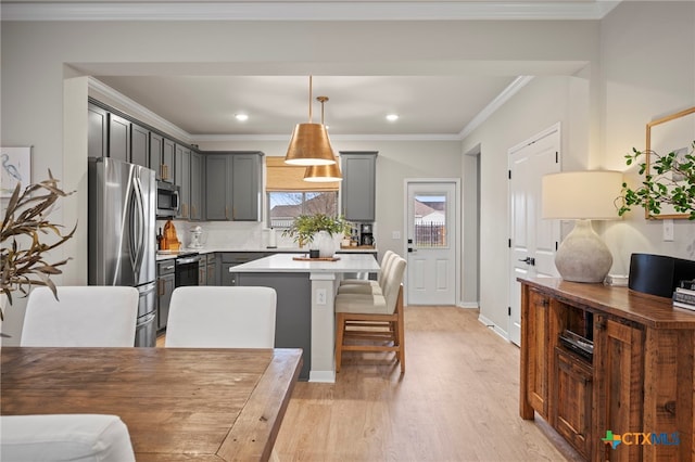 kitchen featuring gray cabinetry, a center island, stainless steel appliances, and light wood-style floors