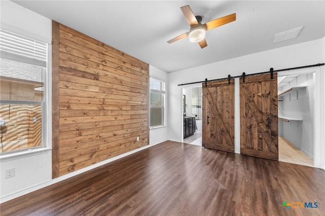 5705 Fenton Ln, Belton, TX 76513 - unfurnished bedroom featuring wood finished floors, a barn door, baseboards, a walk in closet, and ensuite bath