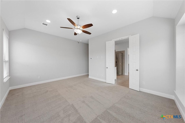 spare room with ceiling fan, a wealth of natural light, light carpet, and lofted ceiling