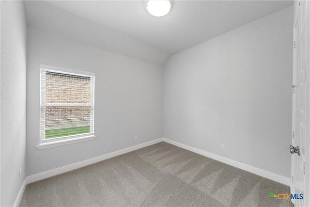 spare room featuring vaulted ceiling and carpet flooring