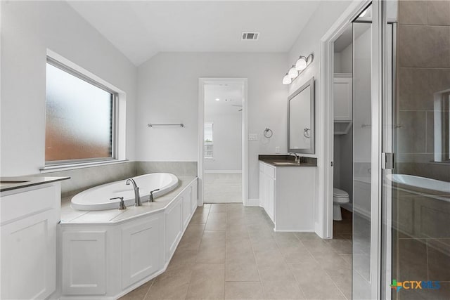 bathroom with toilet, vanity, tile patterned flooring, vaulted ceiling, and a tub