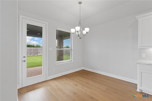 unfurnished dining area featuring light hardwood / wood-style floors and a chandelier