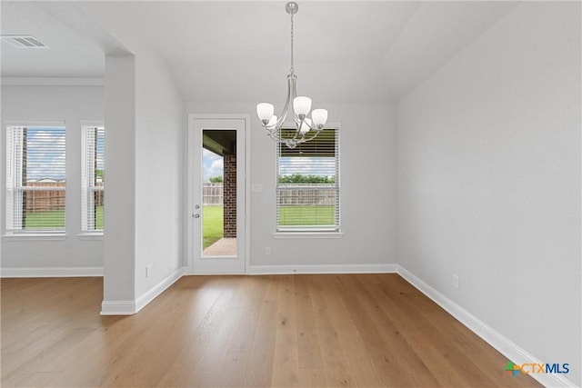 unfurnished dining area with lofted ceiling, light hardwood / wood-style flooring, crown molding, and an inviting chandelier