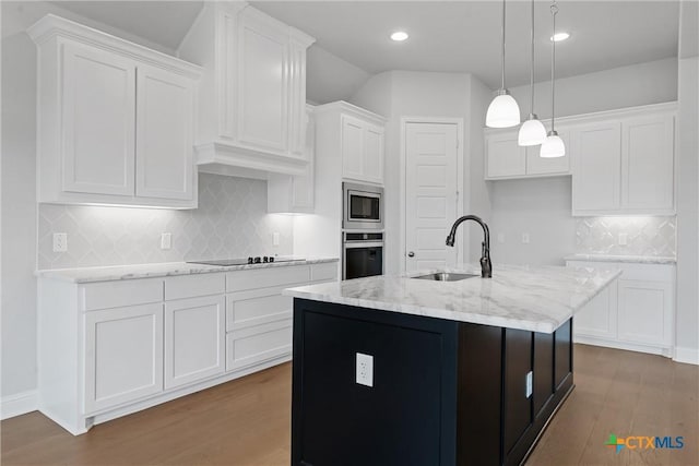 kitchen with stainless steel appliances, a kitchen island with sink, wood-type flooring, white cabinets, and sink