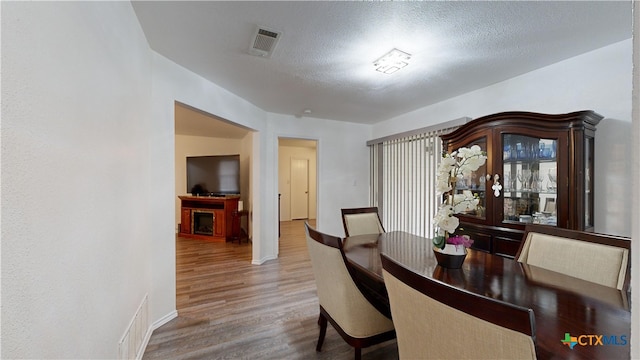 dining room with wood-type flooring and a textured ceiling