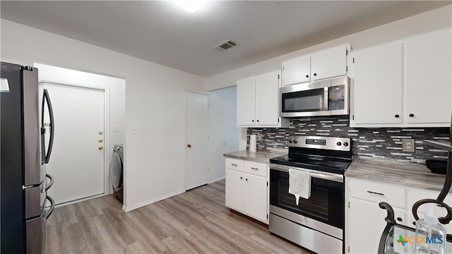 kitchen with white cabinets, decorative backsplash, light wood-type flooring, appliances with stainless steel finishes, and washer / clothes dryer