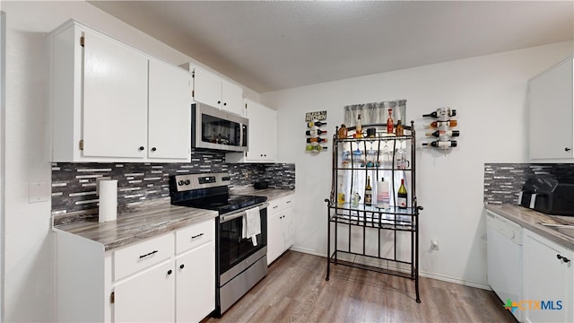 kitchen with stainless steel appliances, light hardwood / wood-style floors, white cabinets, decorative backsplash, and a textured ceiling