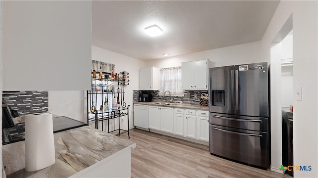 kitchen with decorative backsplash, white cabinetry, stainless steel fridge with ice dispenser, and light wood-type flooring