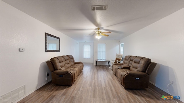 living room featuring a textured ceiling, wood-type flooring, and ceiling fan