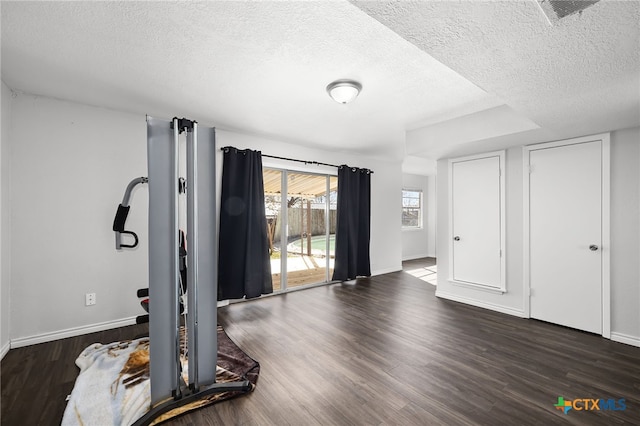 exercise room featuring dark hardwood / wood-style floors and a textured ceiling