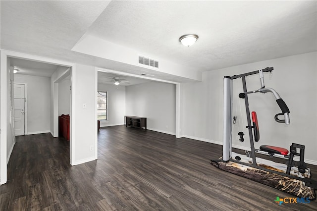 workout room with dark hardwood / wood-style flooring, ceiling fan, and a textured ceiling