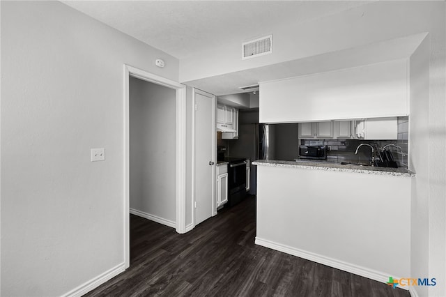 kitchen with range with electric cooktop, dark hardwood / wood-style floors, light stone counters, decorative backsplash, and kitchen peninsula