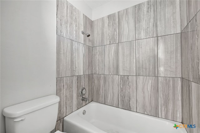 bathroom featuring tiled shower / bath combo and toilet