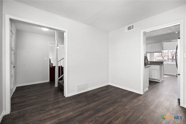 unfurnished bedroom with dark hardwood / wood-style flooring and stainless steel refrigerator