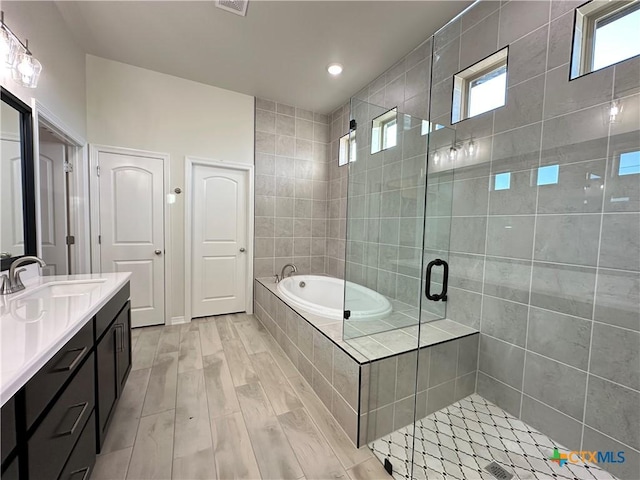 bathroom with hardwood / wood-style floors, vanity, and separate shower and tub