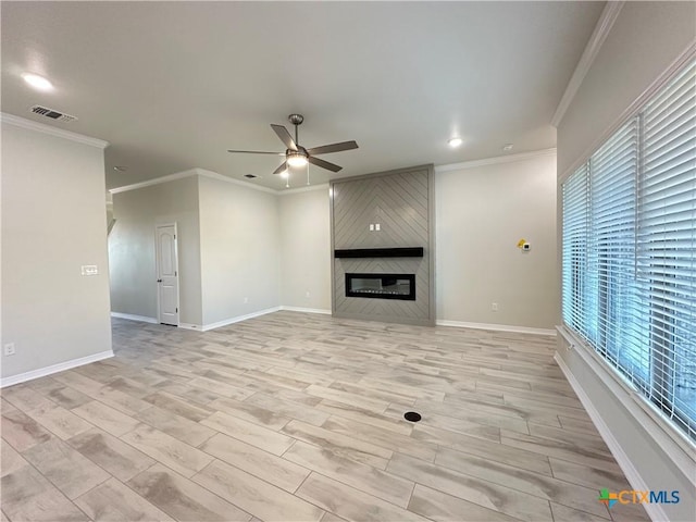 unfurnished living room featuring light wood-type flooring, a large fireplace, ceiling fan, and ornamental molding