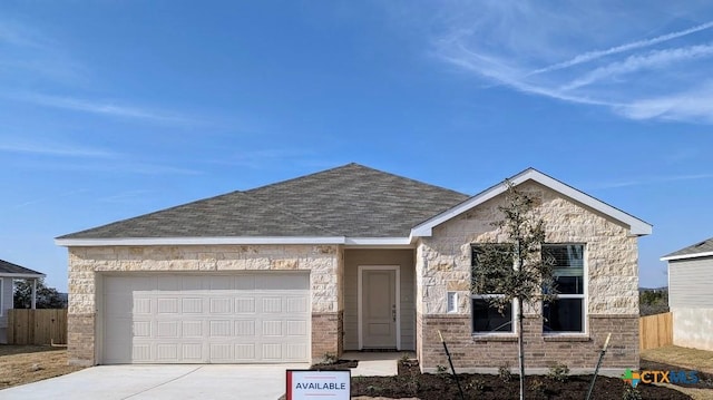 view of front facade with driveway, roof with shingles, an attached garage, and fence