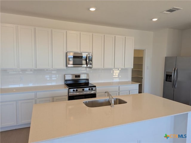 kitchen featuring visible vents, backsplash, light countertops, stainless steel appliances, and a sink