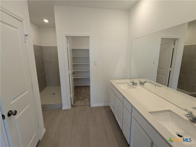 full bathroom with double vanity, a stall shower, wood finished floors, and a sink