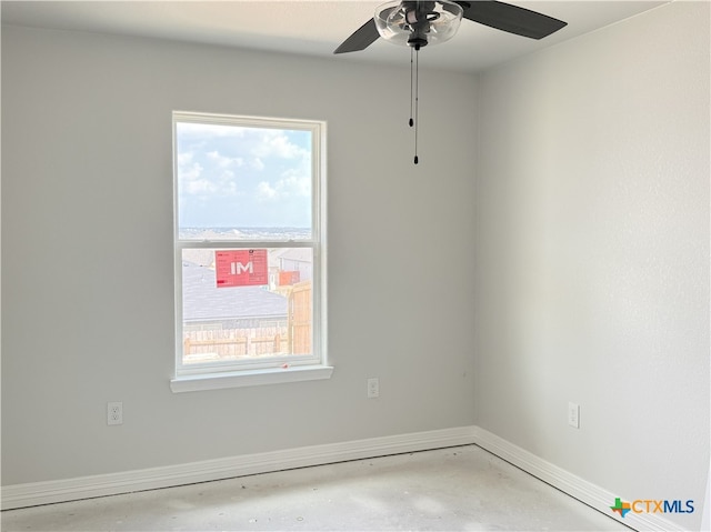 empty room with a healthy amount of sunlight, baseboards, a ceiling fan, and concrete flooring