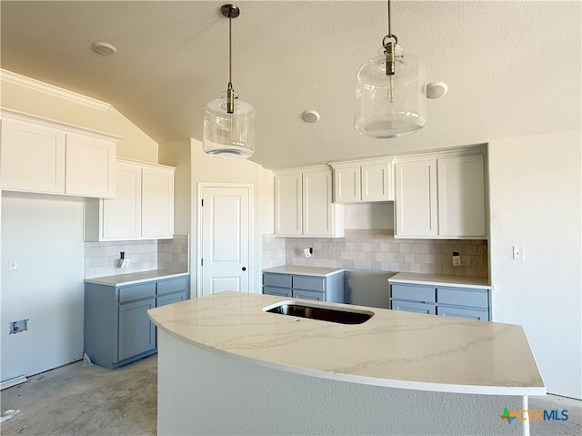 kitchen featuring white cabinets, backsplash, decorative light fixtures, a kitchen island, and vaulted ceiling