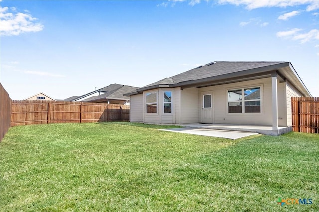 rear view of property with a fenced backyard, a lawn, and a patio