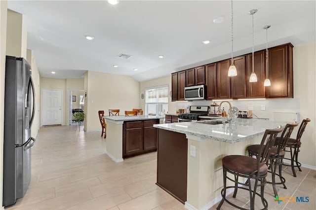 kitchen featuring light stone counters, a peninsula, vaulted ceiling, stainless steel appliances, and a sink