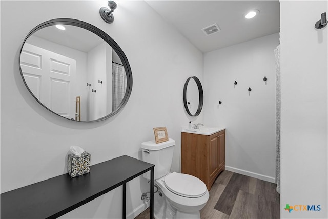 bathroom featuring vanity, wood-type flooring, and toilet