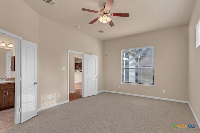 unfurnished bedroom with sink, light colored carpet, ceiling fan, and ensuite bathroom