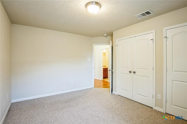 unfurnished bedroom with light carpet, a closet, and a textured ceiling