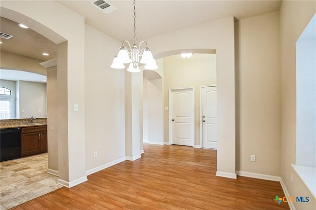 unfurnished dining area featuring sink, a chandelier, and light hardwood / wood-style floors