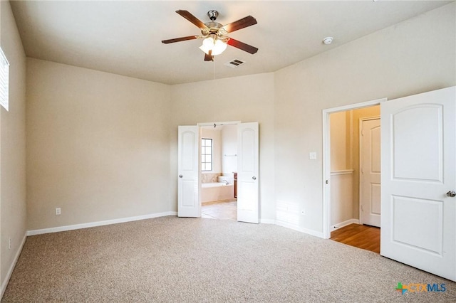 unfurnished bedroom with connected bathroom, light carpet, and ceiling fan