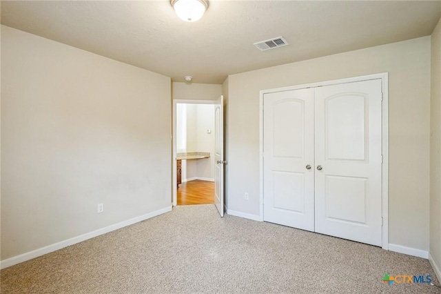 unfurnished bedroom with light colored carpet and a closet