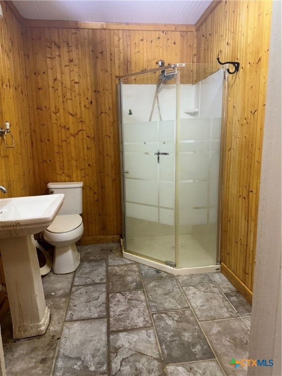 bathroom with wood walls, a shower with shower door, and toilet