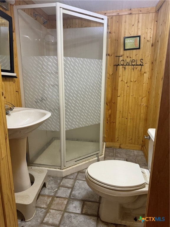 bathroom featuring toilet, wooden walls, and a shower with door