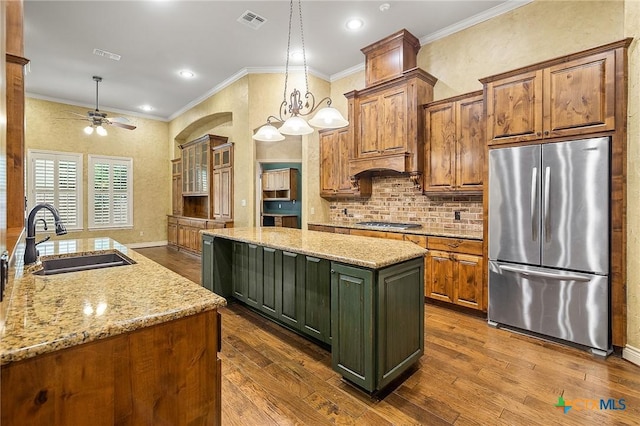 kitchen with a kitchen island, decorative light fixtures, stainless steel appliances, sink, and light stone counters