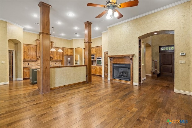 kitchen featuring appliances with stainless steel finishes, a kitchen island, decorative light fixtures, decorative columns, and crown molding