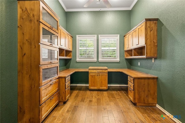 home office featuring built in desk, ceiling fan, and crown molding