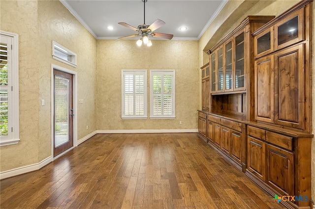 unfurnished dining area with ceiling fan, ornamental molding, and dark hardwood / wood-style flooring